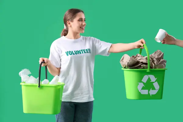 Female volunteer with trash bins on green background. Waste sorting concept