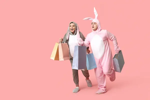 Schönes Junges Paar Hasenkostüm Mit Einkaufstaschen Auf Rosa Hintergrund Osterfest — Stockfoto