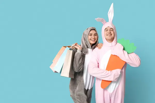 Schönes Junges Paar Hasenkostüm Mit Einkaufstaschen Und Papierkarotte Auf Blauem — Stockfoto