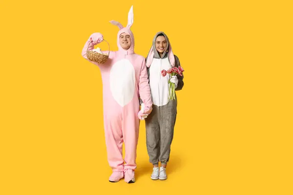 Schönes Junges Paar Hasenkostüm Mit Osterkorb Und Tulpenstrauß Auf Gelbem — Stockfoto