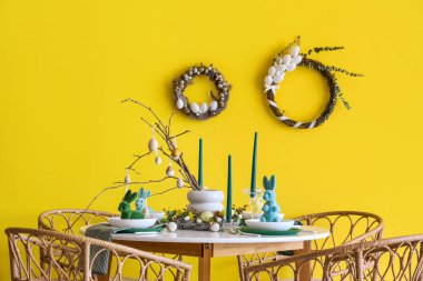 Yemek odasının içinde şenlik masası, sandalyeler ve duvarında Paskalya çelenkleri var.