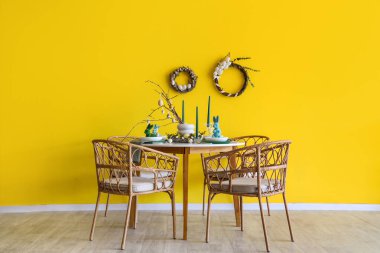 Yemek odasının içinde şenlik masası, sandalyeler ve duvarında Paskalya çelenkleri var.