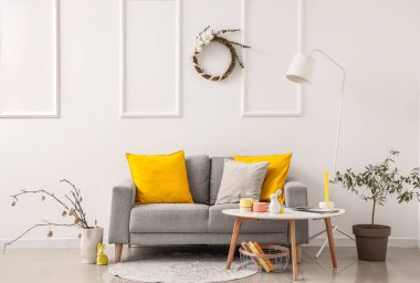 Kanepesi, masası ve duvarında Paskalya çelengi olan şenlikli bir oturma odası.