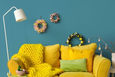 Duvarında kanepe, lamba ve Paskalya çelenkleri olan şık bir oturma odası.