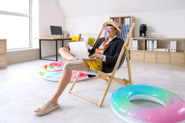 Dizüstü bilgisayarı ve kokteyli olan genç işadamı yaz tatiline hazır.