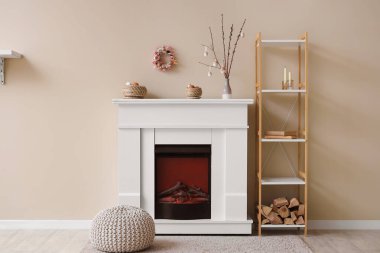 İçinde ağaç dalları olan vazolar ve elektrikli şöminenin üstünde paskalya yumurtaları.