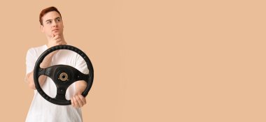 Bej arka planda direksiyon simidi olan düşünceli genç bir adam.