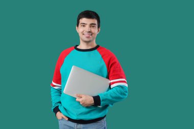 Yeşil arka planda dizüstü bilgisayarı olan erkek programcı