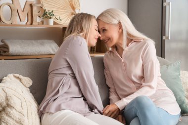 Annesi kanepede oturan ve birlikte vakit geçiren mutlu, genç bir kadın.