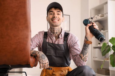 Ofisinde matkap montajı yapan erkek işçi.