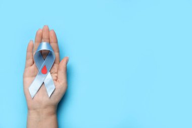 Mavi arka planda farkındalık kurdelesi ve kağıt kan damlası olan bir kadın. Diyabet kavramı