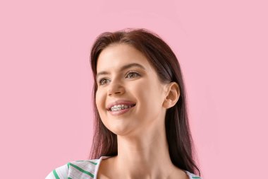 Young woman with dental braces on pink background, closeup clipart