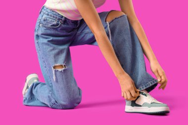Young woman in stylish jeans on purple background clipart
