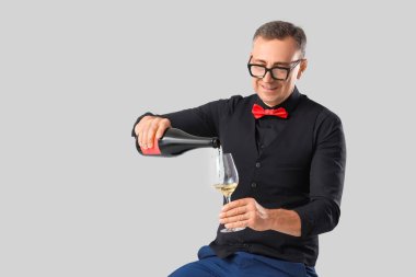 Olgun şarap garsonu açık arkaplanda cama şarap dolduruyor.