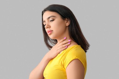 Gri arka planda tiroit bezi sorunu olan genç bir kadın.