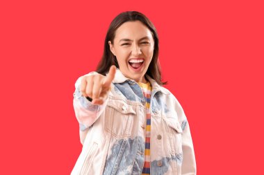 Kırmızı arka plandaki izleyiciyi işaret eden gülen genç bir kadın. Suçlama kavramı