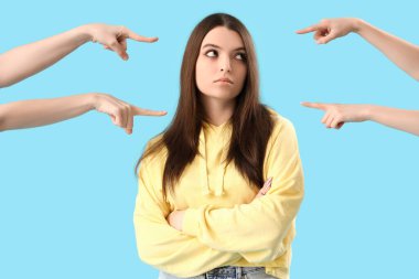 İnsanlar mavi arka plandaki genç kadını işaret ediyor. Suçlama kavramı