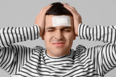 Beyin sarsıntısı geçiren genç bir adam ve arka planda tıbbi yama, yakın plan.