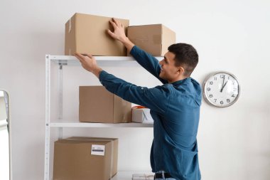 Depodaki rafta bir paket kutusu olan bir erkek çevrimiçi mağaza satıcısı.