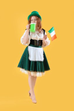 Sarı arka planda bira içen genç İrlandalı garson. Aziz Patrick Günü kutlaması