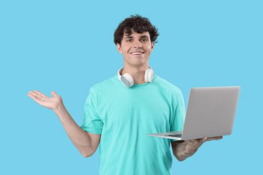 Mavi arkaplanda bir şey gösteren dizüstü bilgisayarı olan erkek programcı