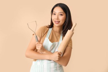 Mutlu, güzel Asyalı kadın, ezici ve bej arka planda oklavalı.