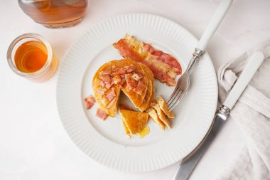 Beyaz arka planda domuz pastırmalı ve akçaağaç şuruplu lezzetli krepler.