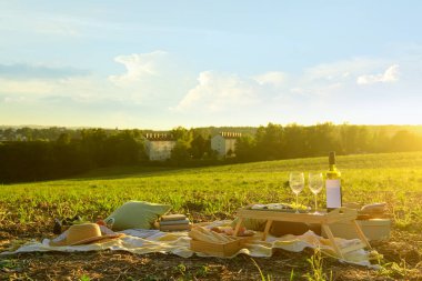 Gün batımında tarlada lezzetli yemekler ve şarapla piknik.