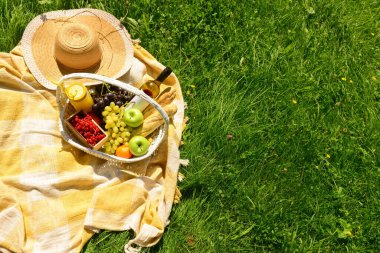 Parkta battaniyede romantik piknik için lezzetli yiyecek ve içeceklerle dolu bir sepet.