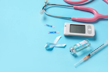 Mavi arka planda insülin, glukometre ve steteskoplu farkındalık şeridi, yakın plan. Diyabet kavramı