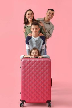 Pembe arka planda bavulu ve ailesi olan küçük çocuklar. Seyahat kavramı