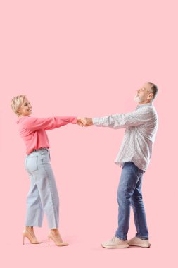 Pembe arka planda dans eden olgun bir çift.