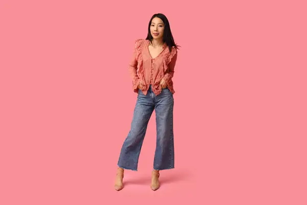 ピンクの背景にスタイリッシュなジーンズで美しい若い幸せなアジアの女性 — ストック写真