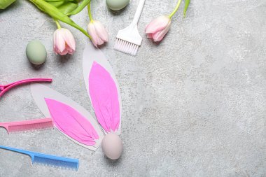 Laleli kuaför aksesuarları, kağıt tavşan kulakları ve gri grunge arka planda Paskalya yumurtaları.