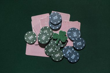 Poker fişleri, şanslı yoncalar ve koyu yeşil arka planda kartlar. Aziz Patrick Günü kutlaması