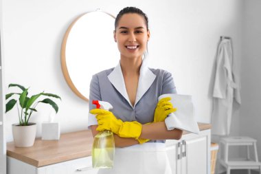 Banyoda deterjanı ve paçavrası olan genç oda hizmetçisi.