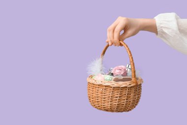 Makyaj ürünleri, çiçekler ve leylak arkaplanda Paskalya dekoru olan kadın el ele tutuşma sepeti.