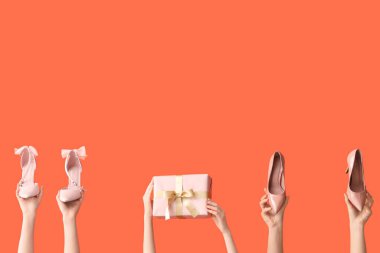 Şık topuklu ve turuncu arka planda hediye kutusu olan kadınlar.