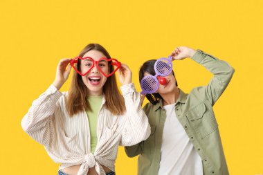 Sarı arka planda komik görünümlü güzel, genç, mutlu kadınlar. 1 Nisan şakası