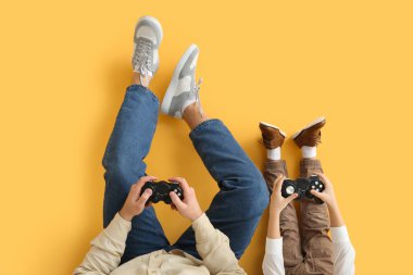 Baba ve küçük oğlu sarı arka planda video oyunu oynuyorlar, yakın plan.