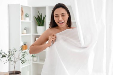 Perdenin arkasındaki genç kadın evde banyo yapıyor.