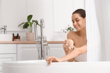 Perdenin arkasında banyo yapan lifi olan genç bir kadın.