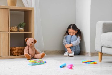 Evde köşede oturan, otistik bozukluğu olan yalnız küçük Asyalı kız.