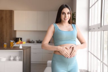 Mutfak penceresinin yanında hamile bir kadın var.