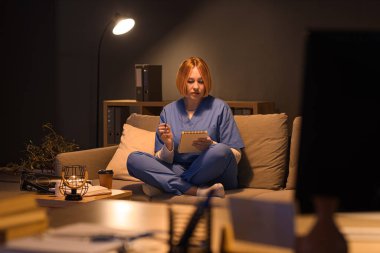 Akşamları hastanedeki kanepede ders çalışan defterli kadın hemşire.