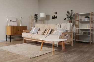 Oturma odasında çekmeceleri ve halısı olan rahat bej bir kanepe.