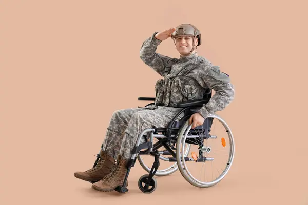 Soldado Masculino Cadeira Rodas Saudando Fundo Bege — Fotografia de Stock