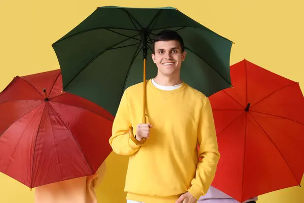 有黄色背景雨伞的年轻人 — 图库照片