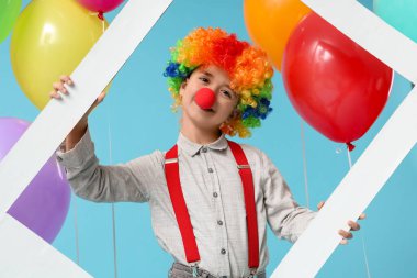 Mavi arka planda çerçevesi olan balonlu palyaço peruğu ve burunlu komik çocuk. 1 Nisan şakası