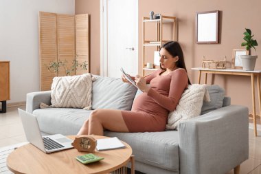 Evdeki not defterine yazan hamile bir kadın. Annelik Faydası kavramı